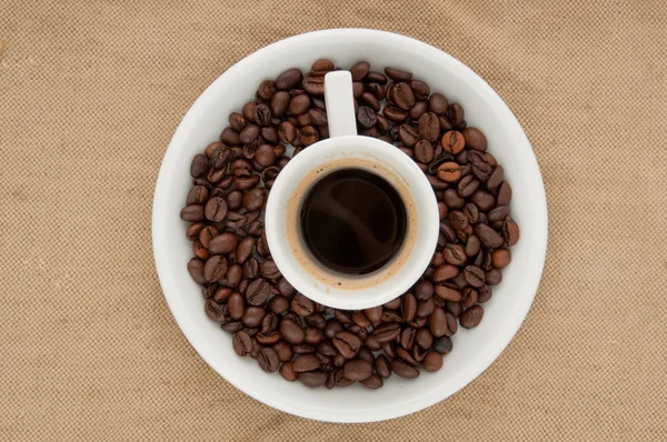コーヒー豆を背景にコーヒーを飲みながら — ストック写真