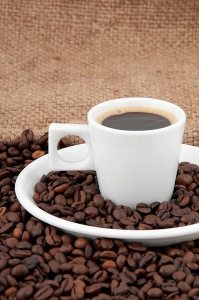 Una taza de café en el fondo de granos de café — Foto de Stock