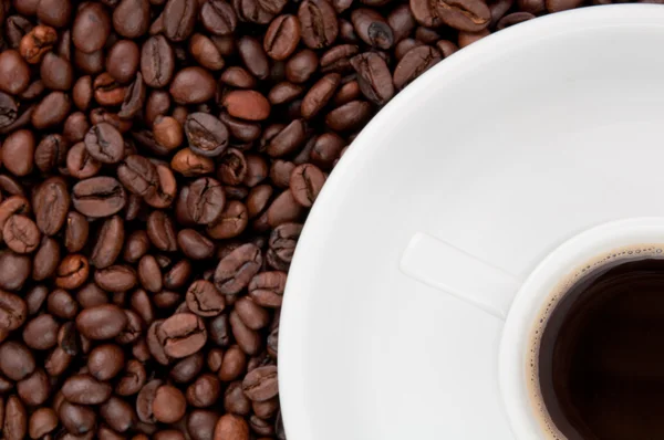 Una taza de café en el fondo de granos de café — Foto de Stock