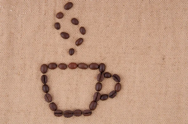 Una taza de granos de café con humo en el fondo de la arpillera . — Foto de Stock