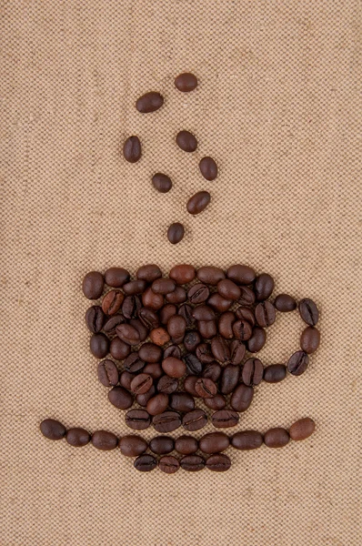 Una tazza di chicchi di caffè con fumo sullo sfondo di iuta . — Foto Stock