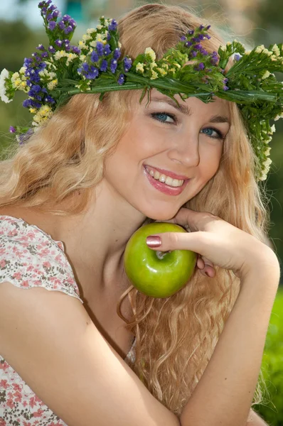 A beautiful blonde young woman with a wreath on his head eating — Stock Photo, Image