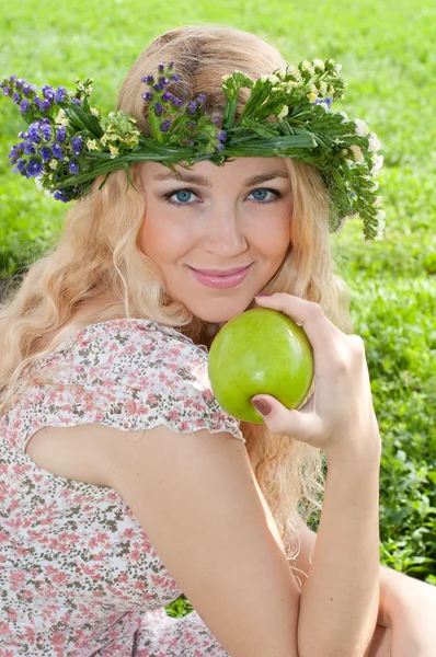 A beautiful blonde young woman with a wreath on his head eating — Stock Photo, Image