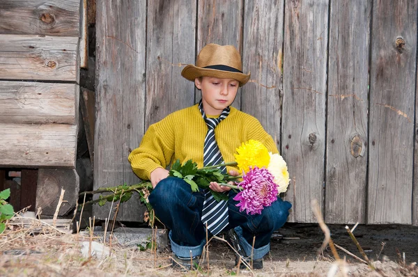 木の塀に対して菊の花束を持つ少年. — ストック写真