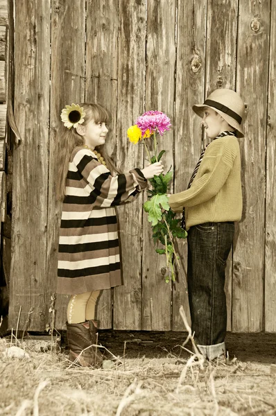 De jongen geeft een meisje bloemen. eerste liefde. — Stockfoto