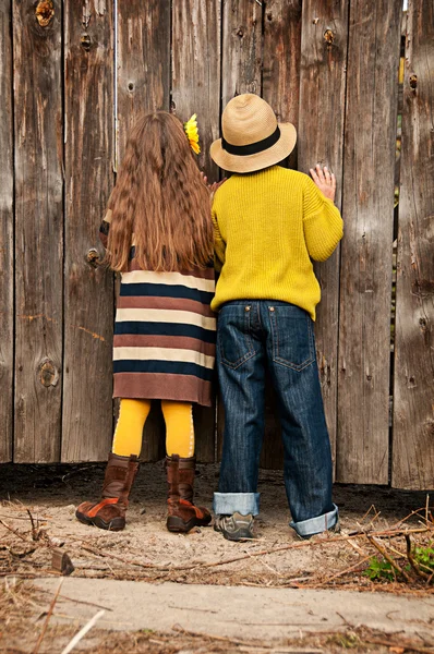 The boy with the girl peep over the fence. Photos in the old style. — Stock Photo, Image