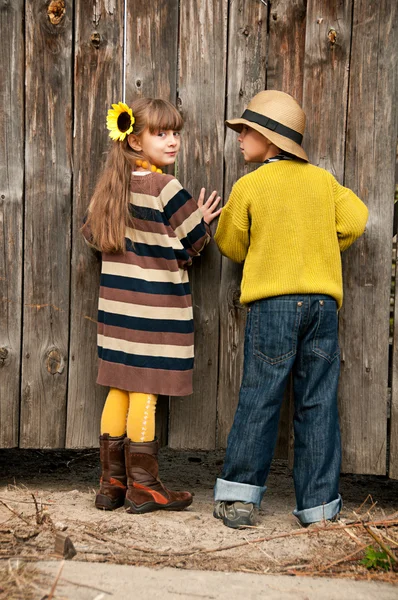 De jongen met de meisje peep over het hek. foto's in de oude stijl. — Stockfoto