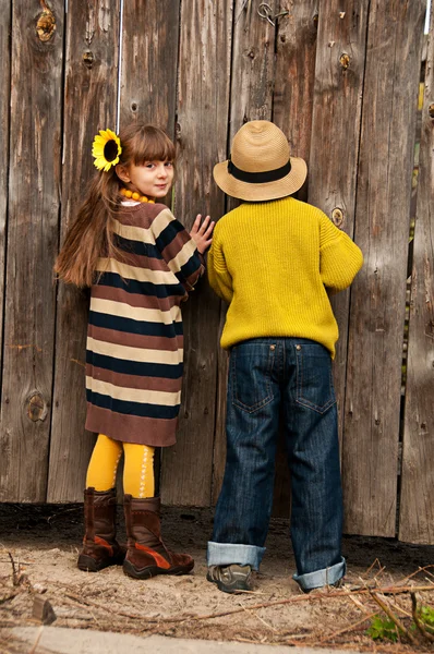 The boy with the girl peep over the fence. Photos in the old style. — Stock Photo, Image