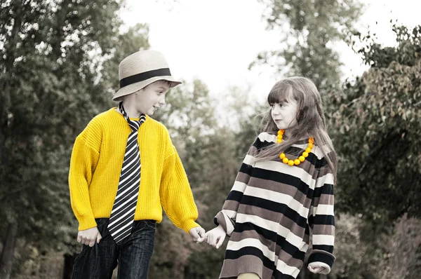 De jongen met het meisje gaan op de weg die hand in hand. — Stockfoto