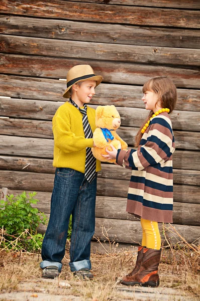 O menino com a menina de pé perto de uma cerca de madeira . — Fotografia de Stock