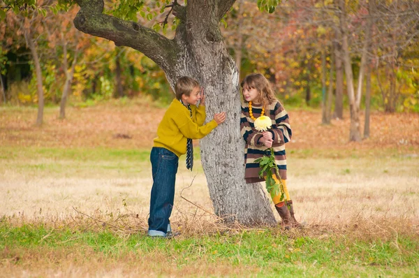 El chico con la chica de pie cerca de un árbol . —  Fotos de Stock