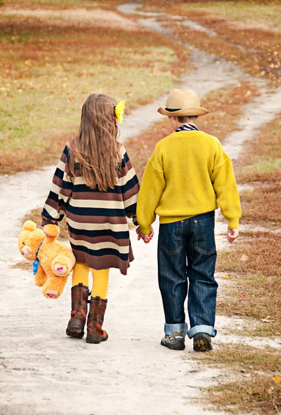 O menino com a menina vai na estrada de mãos dadas . — Fotografia de Stock