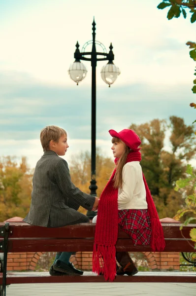 O rapaz com a rapariga sentada no banco. Um encontro romântico . — Fotografia de Stock
