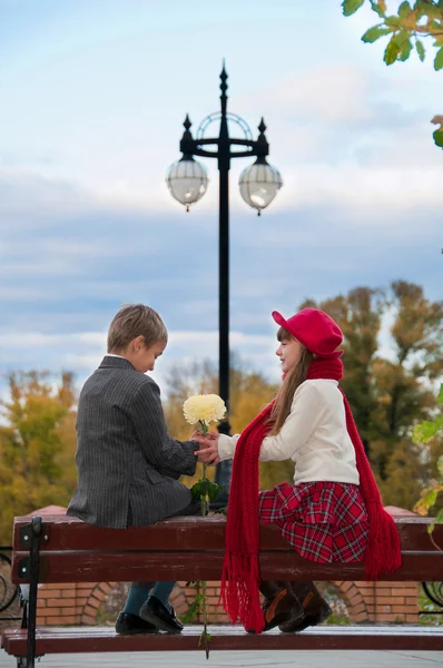 El chico con la chica sentada en el banco. Una cita romántica . — Foto de Stock