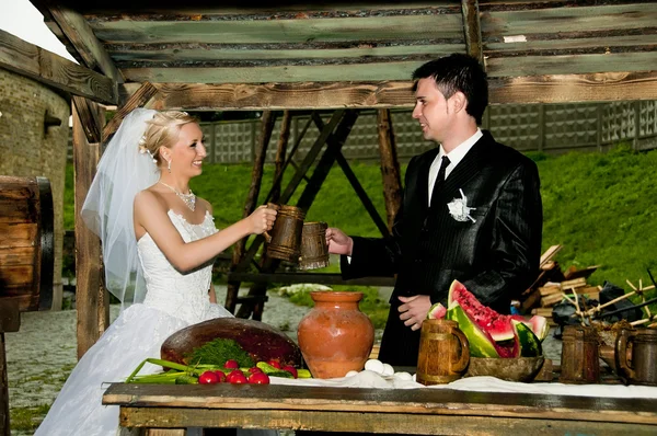 stock image The bride and groom happy drinking from wooden cups.