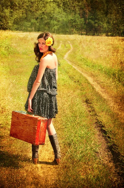 Krásná brunetka s kufrem na venkově. fotografie v — Stock fotografie