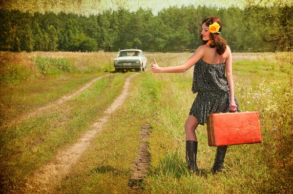 Beautiful brunette with a suitcase in the countryside. Photos in — Stock Photo, Image