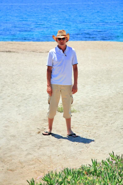 Young man in sunglasses in a straw hat on the beach — Stock Photo, Image