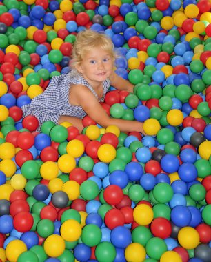 Happy girl playing in balls. clipart