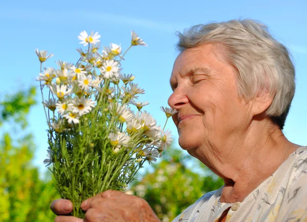 Senior riecht Blumen. — Stockfoto