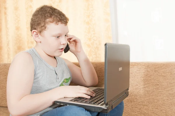 Мальчик с телефоном и компьютером — стоковое фото