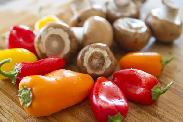 Mushrooms and colorful peppers waiting to be cut. — Stock Photo, Image