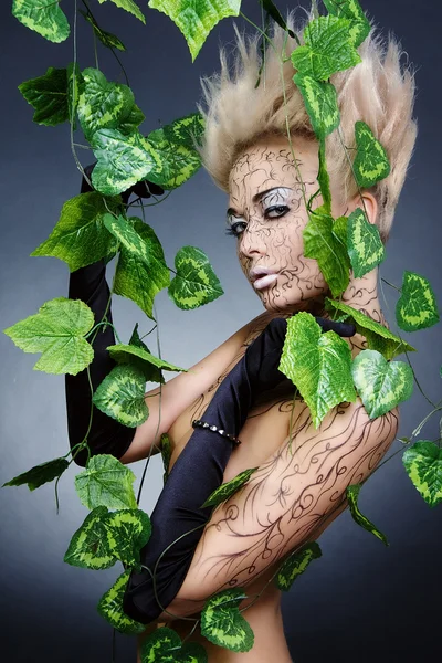 Hermosa chica con el pelo corto, guantes de bálsamo, en hojas verdes . — Foto de Stock