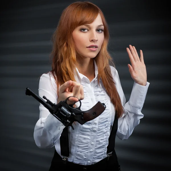 Dívka s červenými vlasy dává revolver — Stock fotografie