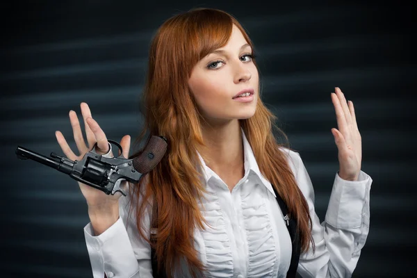 Mooi meisje met rode haren geeft een revolver — Stockfoto