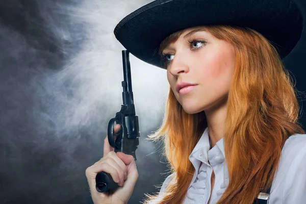 Das schöne Mädchen mit Hut, mit einem Revolver. Stockbild