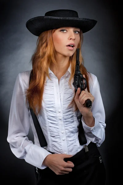 Menina bonita com cabelo vermelho desempenha um revólver — Fotografia de Stock