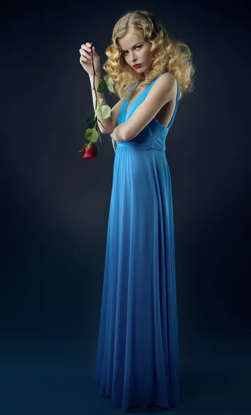 Mooi meisje in donker blauwe jurk met roos — Stockfoto
