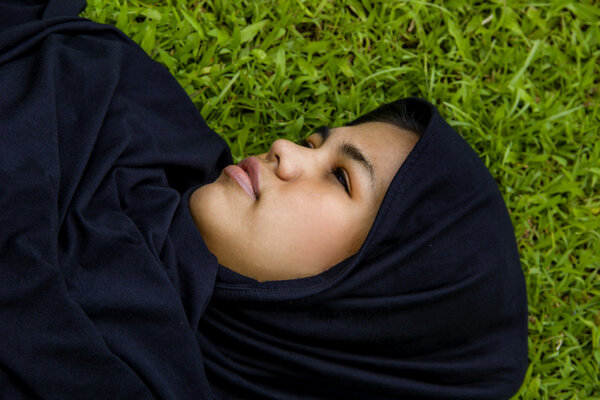 Indonesian moslim girl, laying on the grass