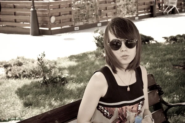 Het jonge meisje zit op een bankje — Stockfoto