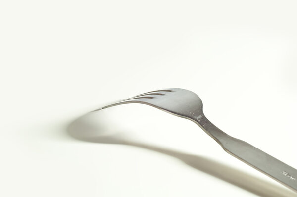 Metallic fork and her shadow on the white background