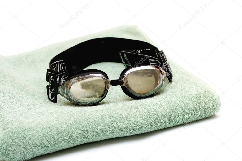 Glasses for swim lay on the towel on white