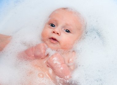 Newborn child in a bath with soapsuds clipart