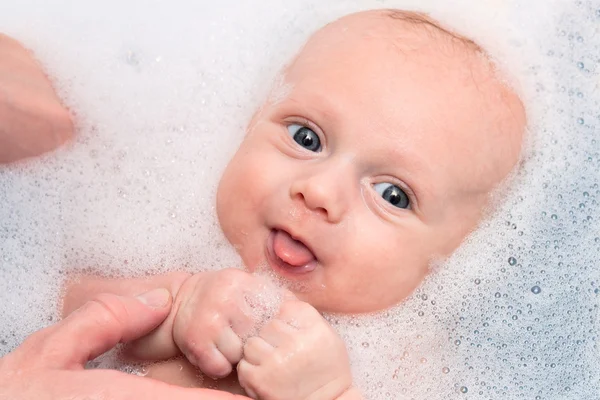 Bébé garçon se baignant dans des savons avec la langue — Photo