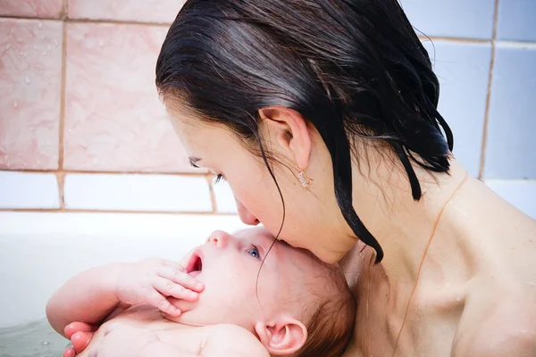 Mère embrasse bébé dans une salle de bain — Photo