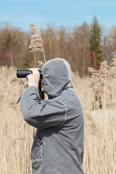 Man met verrekijker kijken naar de vogels in de buurt van het meer — Stockfoto