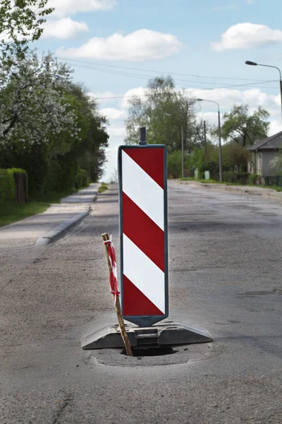 Segnale di avvertimento stradale sulla strada vicino alla fossa — Foto Stock