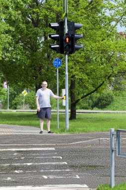 Man waiting for the green light to cross the pedestrian crossing clipart