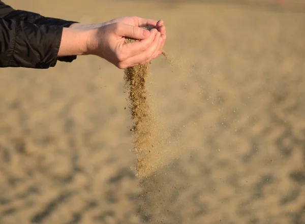 Zand gemorst uit de handen Stockfoto