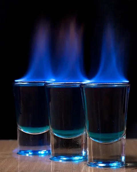 Bebida quemada en un vaso de chupito sobre una mesa —  Fotos de Stock