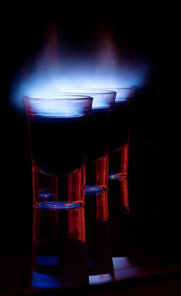 Bebida ardente em vidro de tiro em uma mesa — Fotografia de Stock