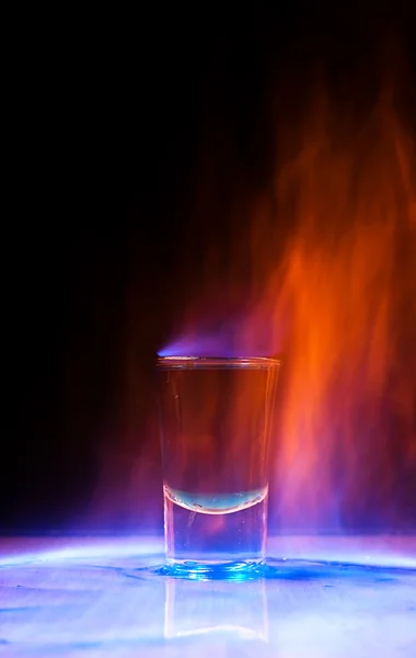 Bebida quemada en un vaso de chupito sobre una mesa —  Fotos de Stock