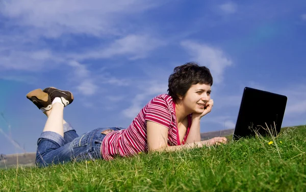 Unga casual kvinna som arbetar på laptop utomhus — Stockfoto