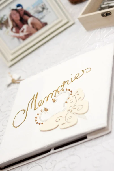 White photo album with Memories written with golden font and blurred picture of couple in the background — Stock Photo, Image