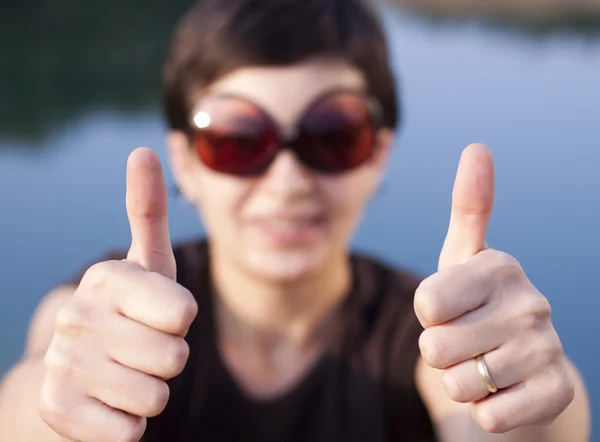 Menina morena nova com grandes óculos de sol engraçados fazendo polegares para cima gesto — Fotografia de Stock
