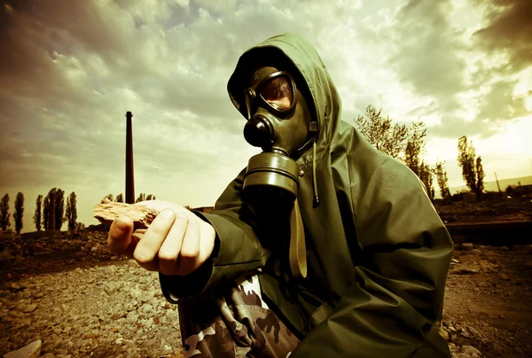 Scientist with gas mask examining rock in destroyed territory after explosi — Stock Photo, Image